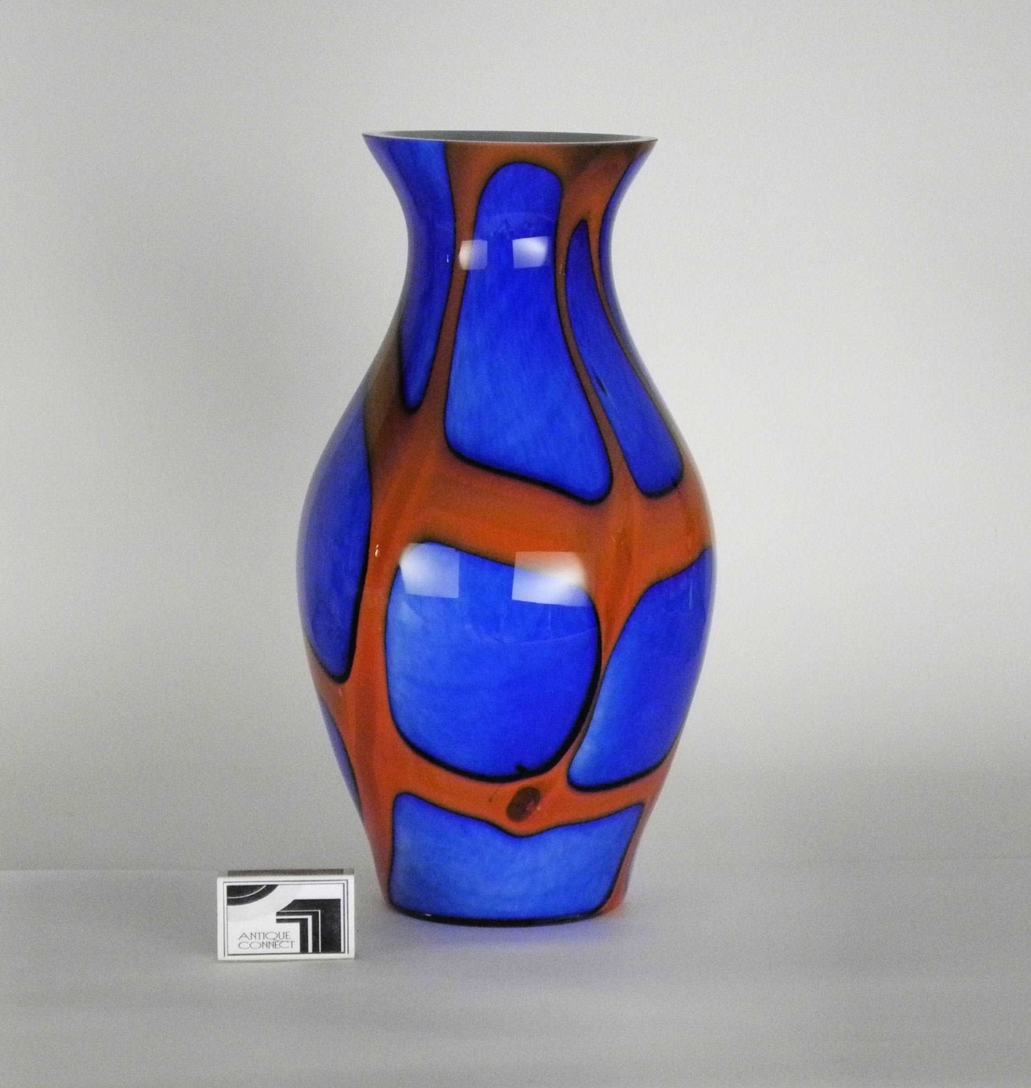 Grosse blaue Krugvase mit roten Bändern.