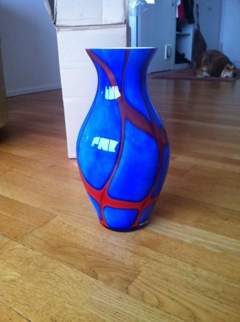 Grosse blaue Krugvase mit roten Bändern.