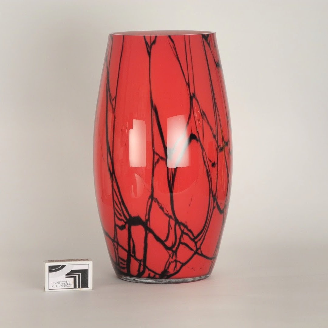 Runde rote Vase mit schwarzen Streifen.