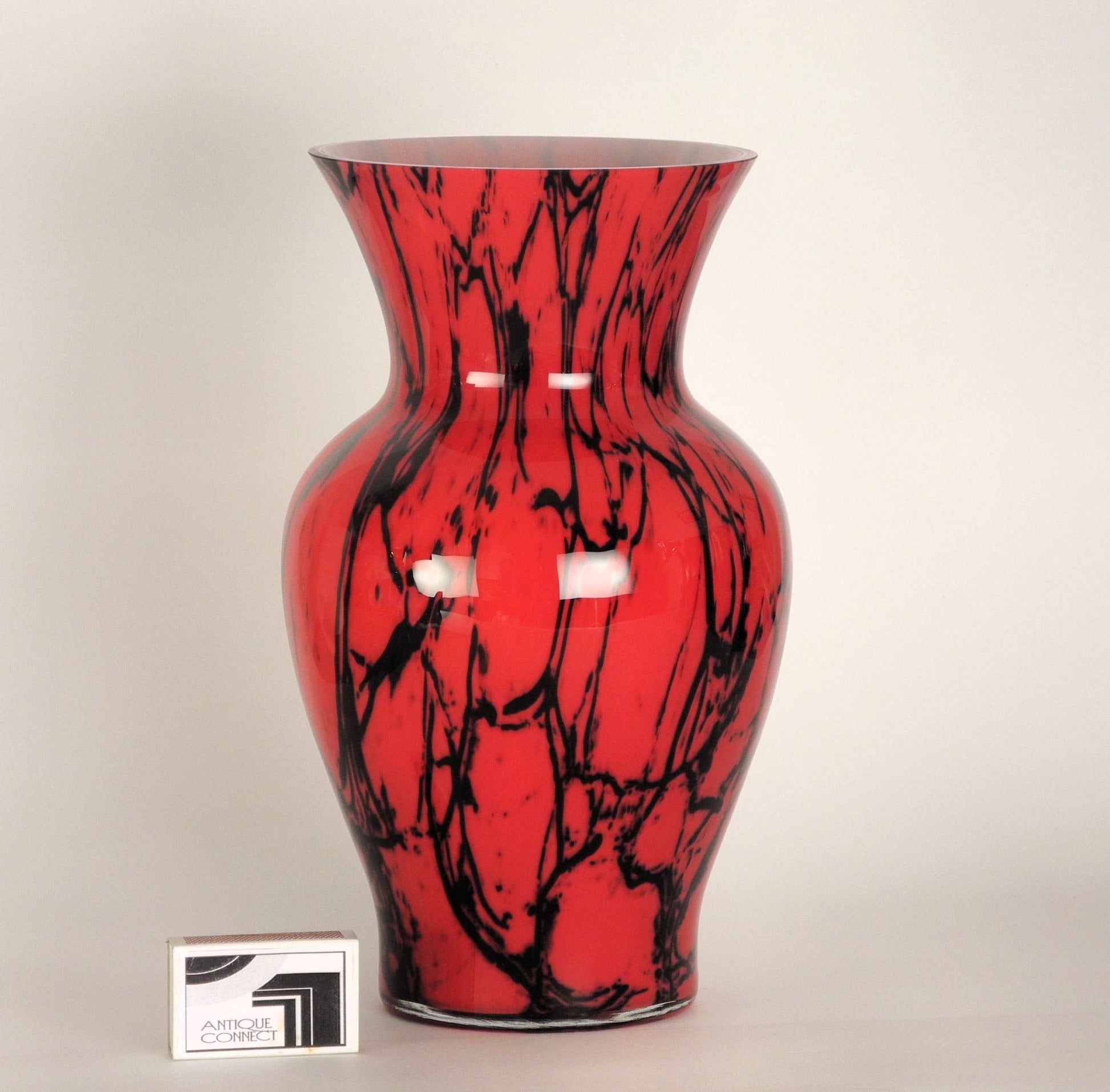 Rote Vase mit schwarzem Dekor.